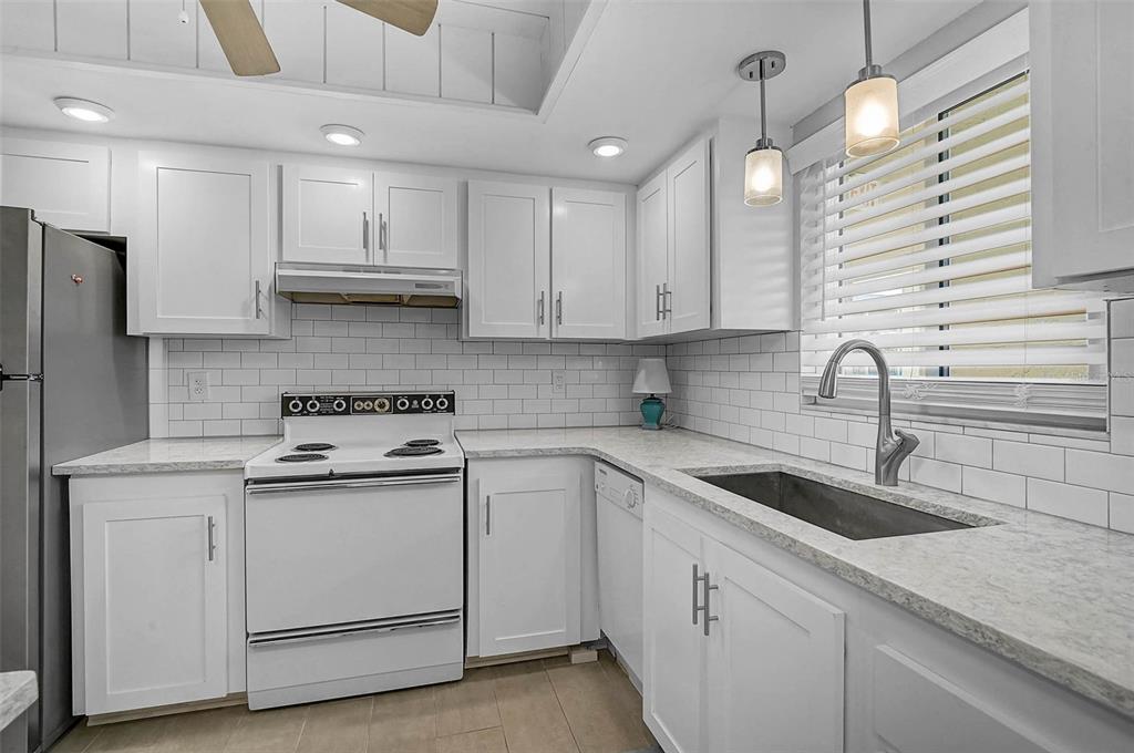 A kitchen with white cabinets, light countertops, subway tile backsplash, and stainless steel appliances — 3585 LAKE BAYSHORE DRIVE UNIT J-301, BRADENTON, FL