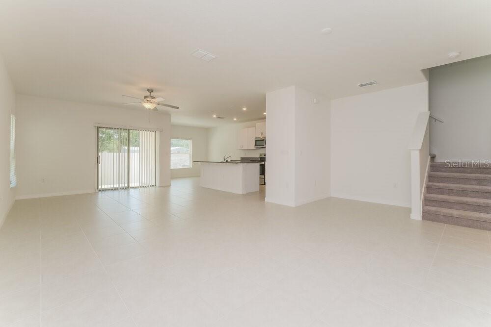 An open-concept living area with tile flooring, a kitchen island, and carpeted stairs — 7337 SPRING SNOWFLAKE AVENUE, TAMPA, FL