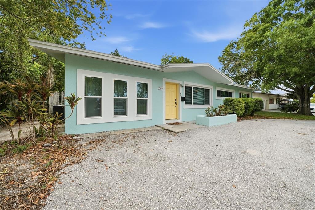 A light blue single-story house with a yellow front door and a gravel driveway — 2489 58TH STREET N, ST PETERSBURG, FL