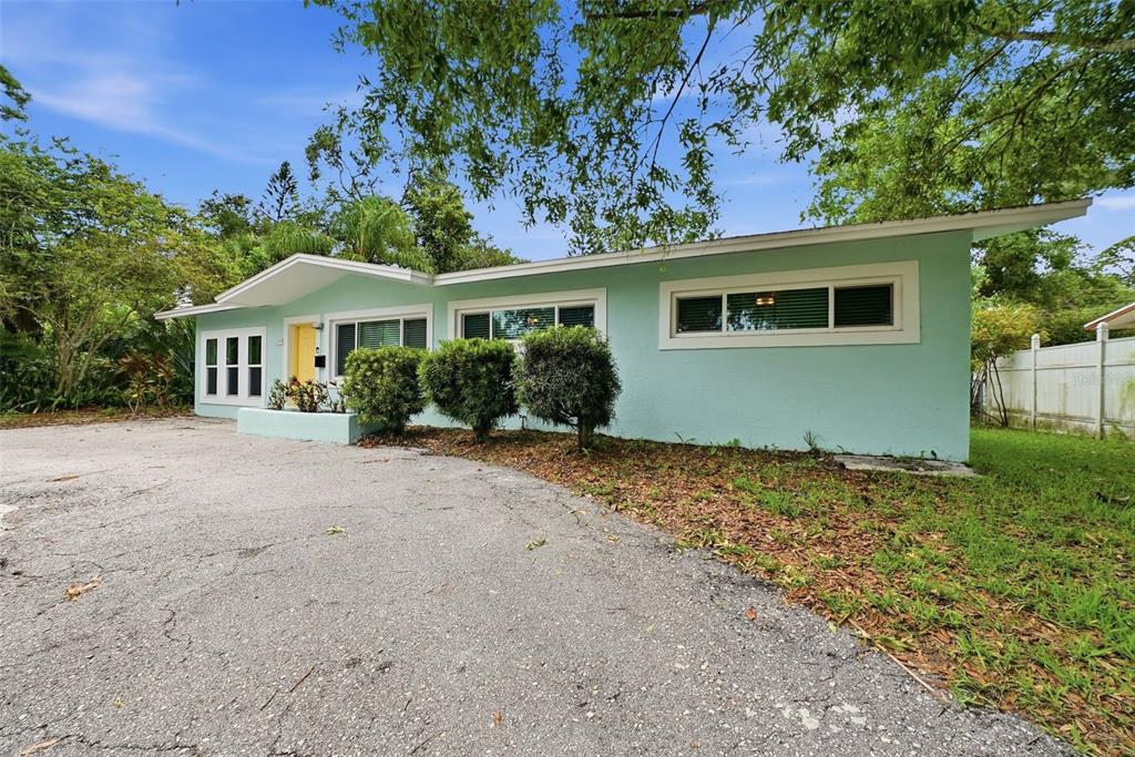 A single-story, light green house with a yellow front door and a paved driveway — 2489 58TH STREET N, ST PETERSBURG, FL
