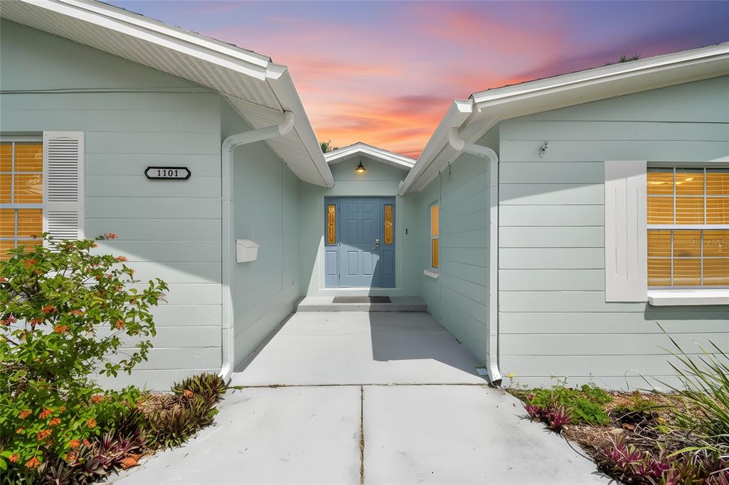 The exterior of a light blue house features a recessed entryway with a blue door — 1101 81ST AVENUE N, ST PETERSBURG, FL