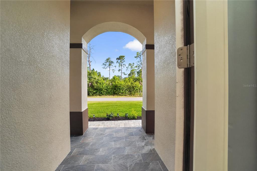 A covered entryway with tiled flooring leads to an outdoor view of a grassy yard — 12252 DIETRICH AVENUE, PORT CHARLOTTE, FL