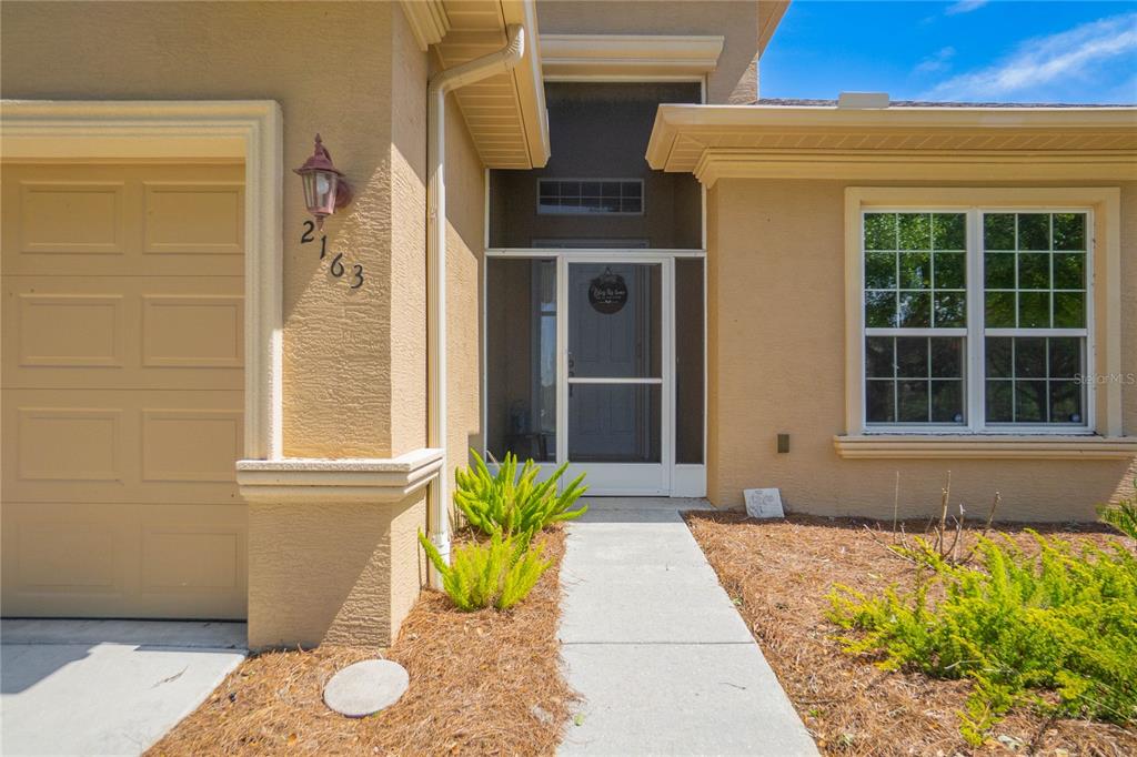 The exterior of a tan house features a garage, a screened entryway, and a walkway — 2163 N BRENTWOOD CIRCLE, LECANTO, FL