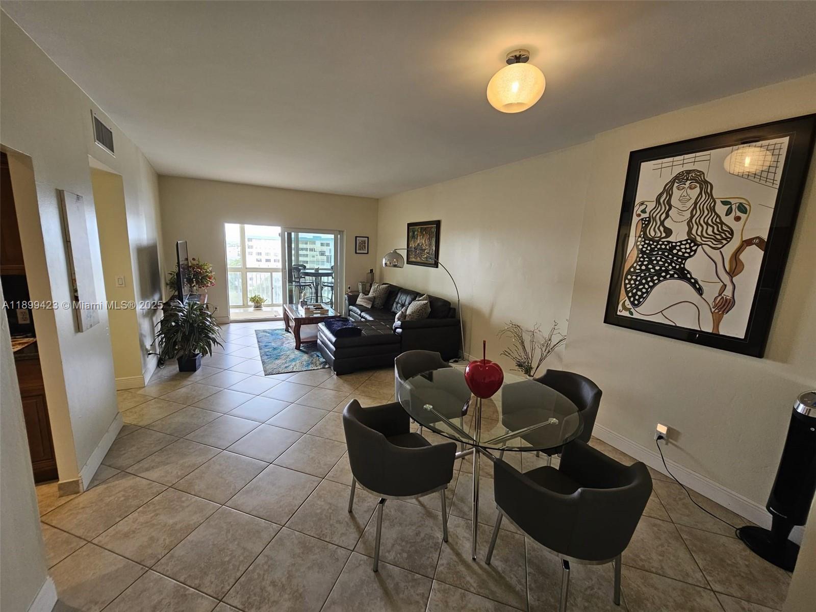 A living and dining area features tile flooring, a glass table, and a sectional sofa — 4200 Hillcrest Dr # 1015, Hollywood FL 33021, HOLLYWOOD, FL