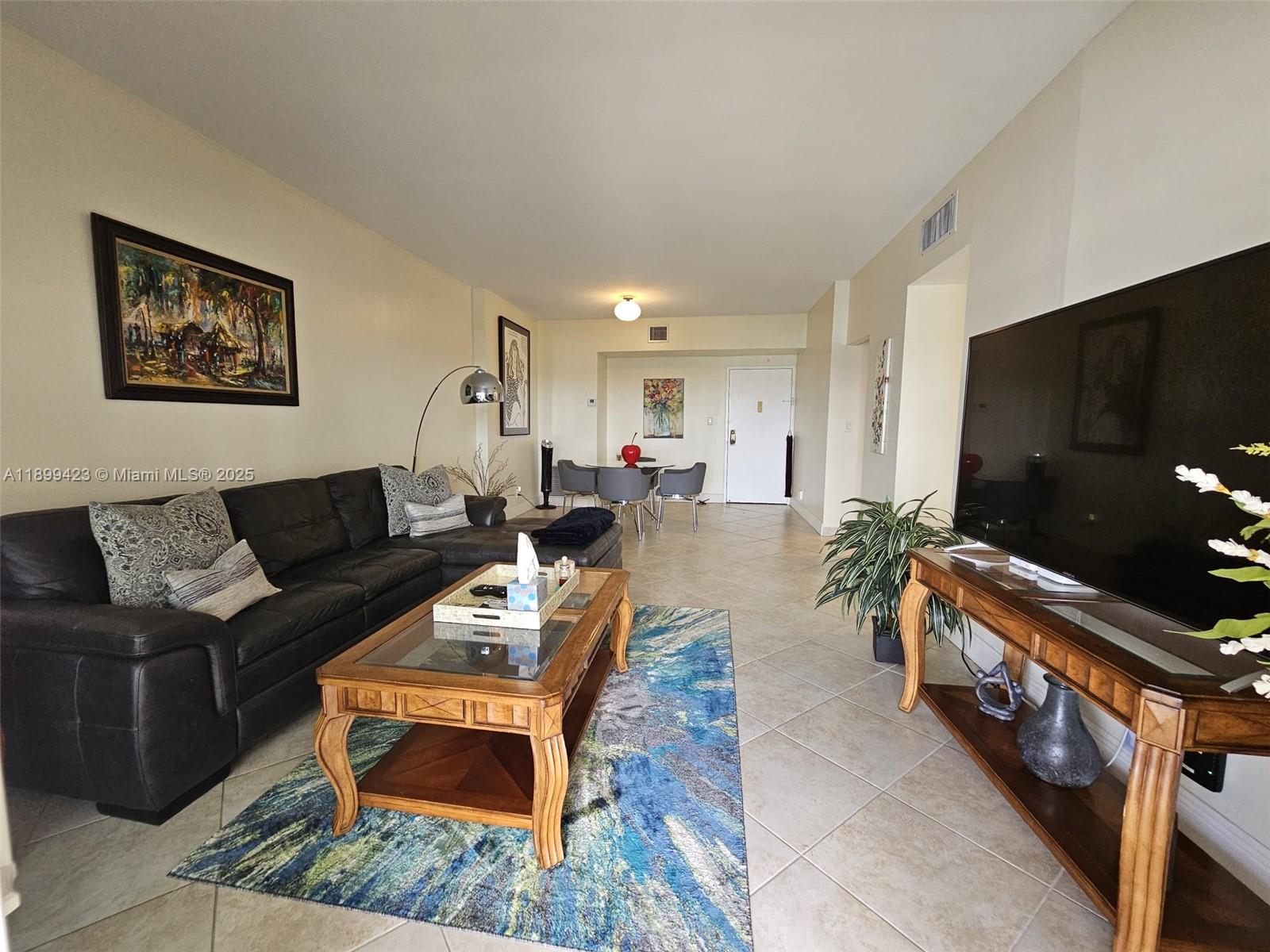 A living room features a dark sectional sofa, a wooden coffee table, and a dining area — 4200 Hillcrest Dr # 1015, Hollywood FL 33021, HOLLYWOOD, FL
