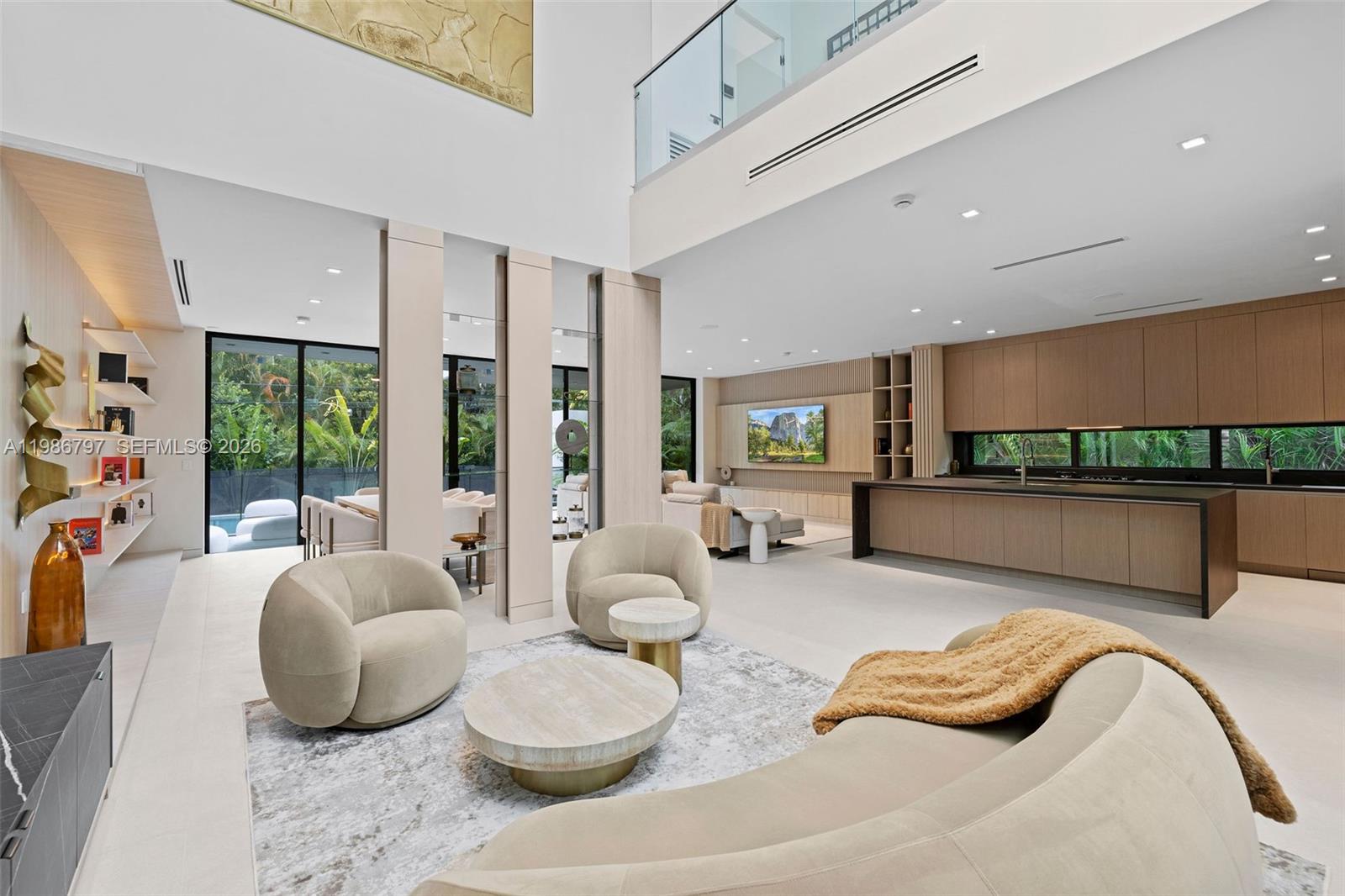A modern, open-concept living room and kitchen feature high ceilings, light wood cabinetry, and furniture — 4534 Sheridan Ave, Miami Beach FL 33140, MIAMI BEACH, FL