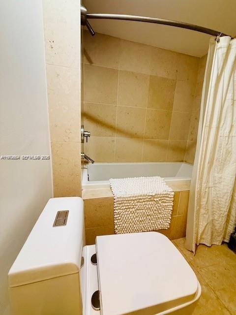 A bathroom features a white toilet, a beige tiled bathtub, and a shower curtain — 475 Brickell Ave # 4910, Miami FL 33131, MIAMI, FL
