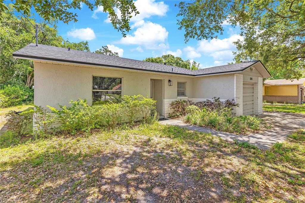 A single-story house with a beige stucco exterior, a gray roof, and a garage — 1725 CALIFORNIA AVENUE, ST CLOUD, FL