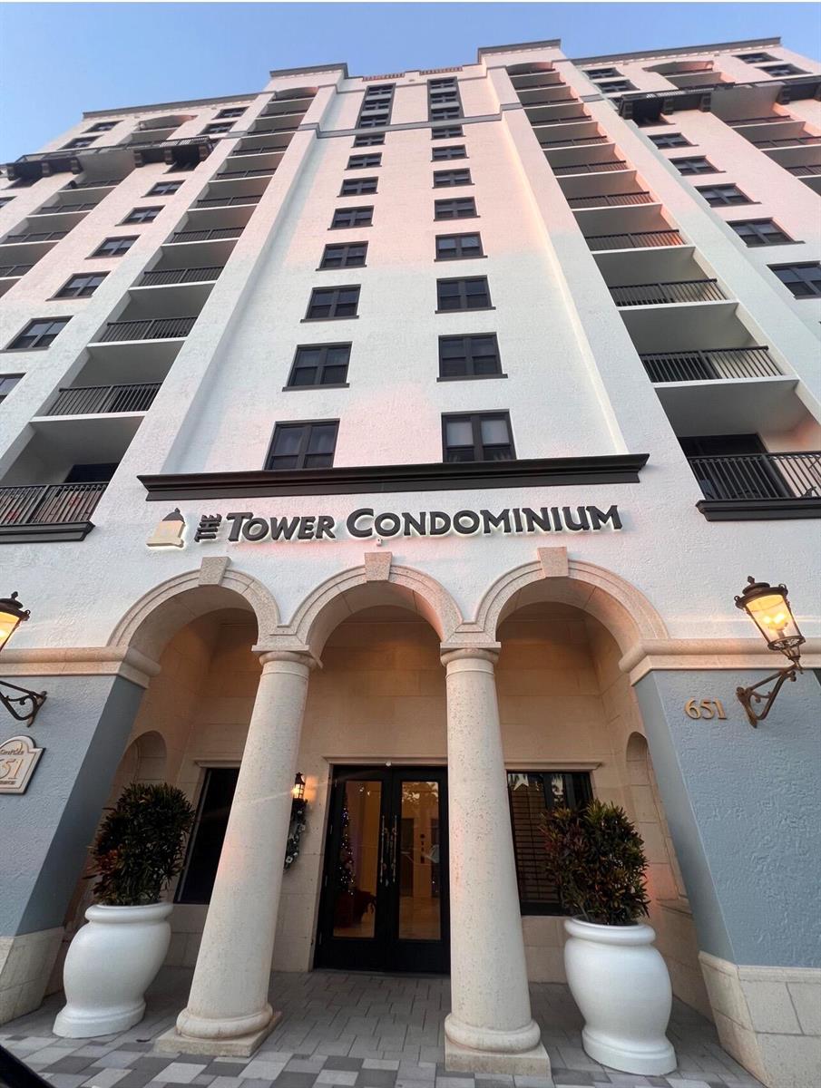 A low-angle view of a multi-story condominium building entrance with arched columns and balconies — 651 Okeechobee Boulevard # 706, West Palm Beach FL 33401, WEST PALM BEACH, FL