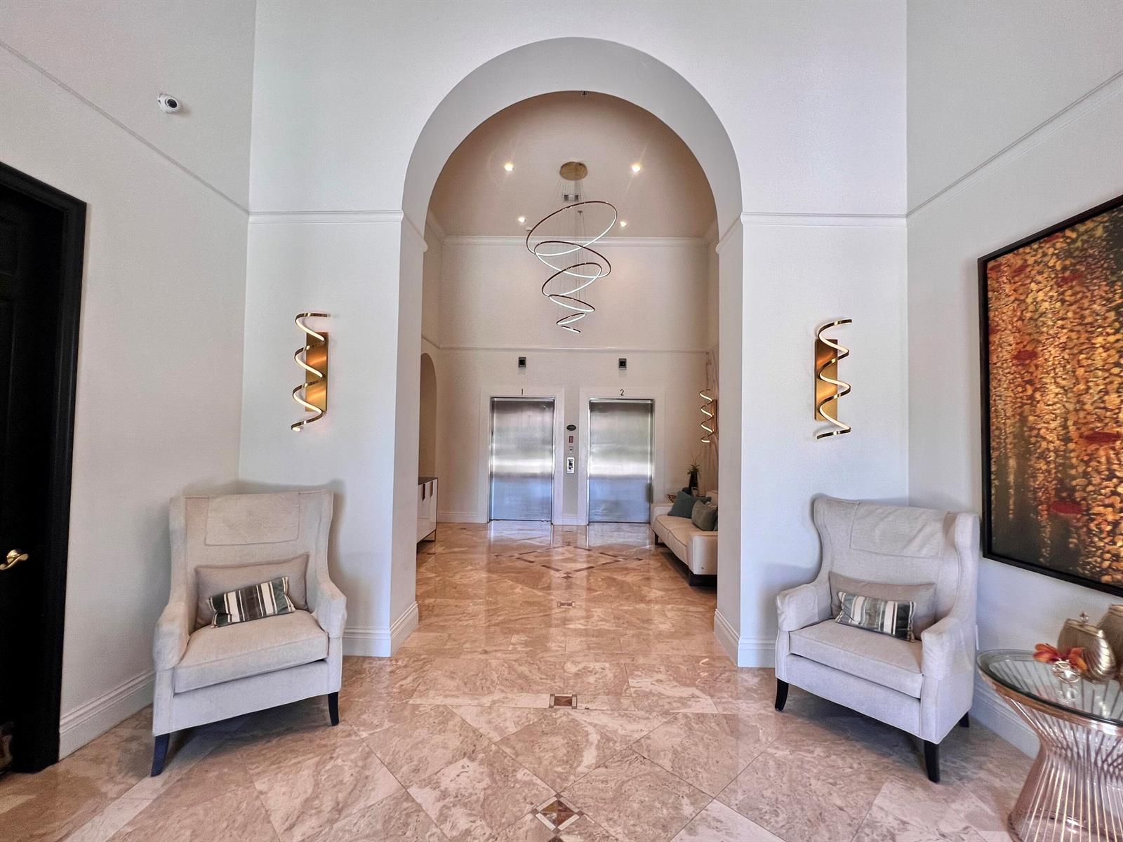 A symmetrical lobby features two armchairs, a central arched entryway, and two stainless steel elevators — 651 Okeechobee Boulevard # 706, West Palm Beach FL 33401, WEST PALM BEACH, FL