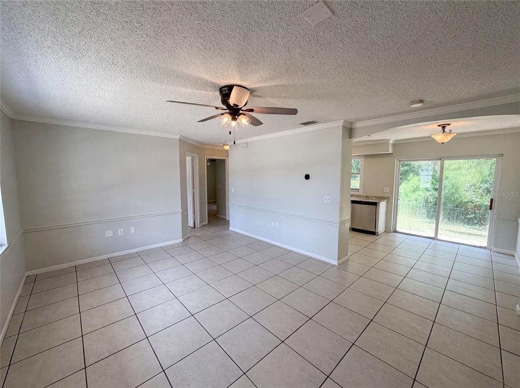 An open-concept living area features light-colored tile floors, a ceiling fan, and a kitchen view — 3730 DEDRICK COURT, NEW PORT RICHEY, FL