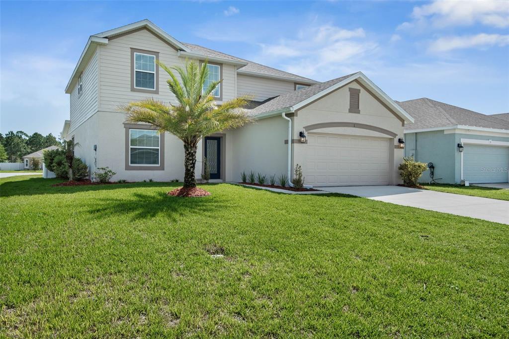 A two-story suburban house with a beige stucco and siding exterior and a two-car garage — 1 RIDGE ROAD, PALM COAST, FL
