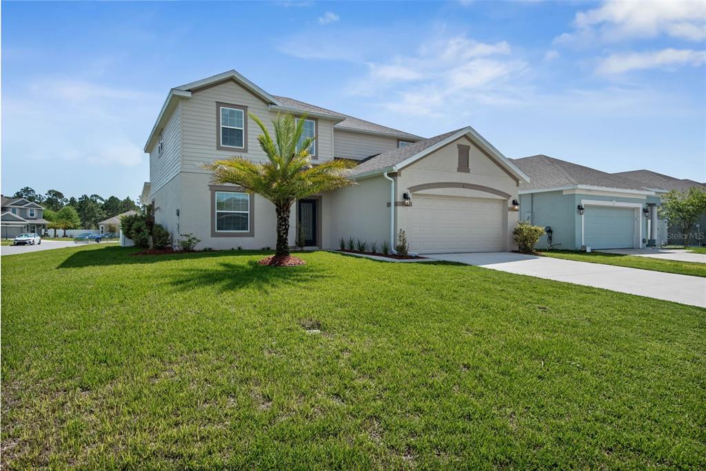 A two-story suburban house with a beige stucco and siding exterior and a two-car garage — 1 RIDGE ROAD, PALM COAST, FL