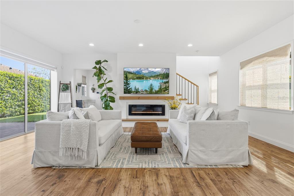 A living room features two white sofas, a leather ottoman, and a fireplace with a television — 10254 BEECHWOOD LANE, ORLANDO, FL