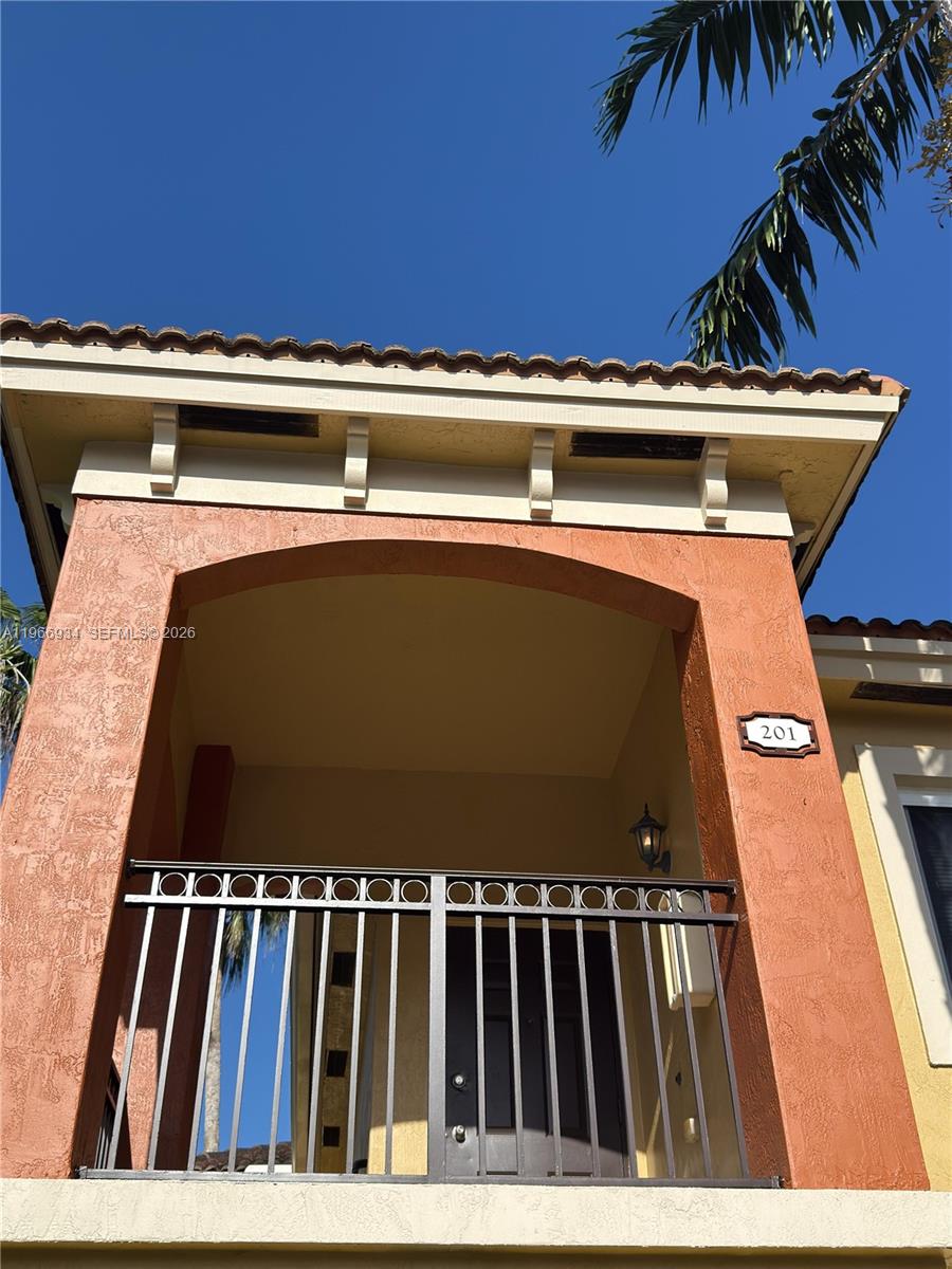 A second-story balcony with a metal railing and an arched entryway is shown — 930 NE 34th Ave # 201, Homestead FL 33033, HOMESTEAD, FL