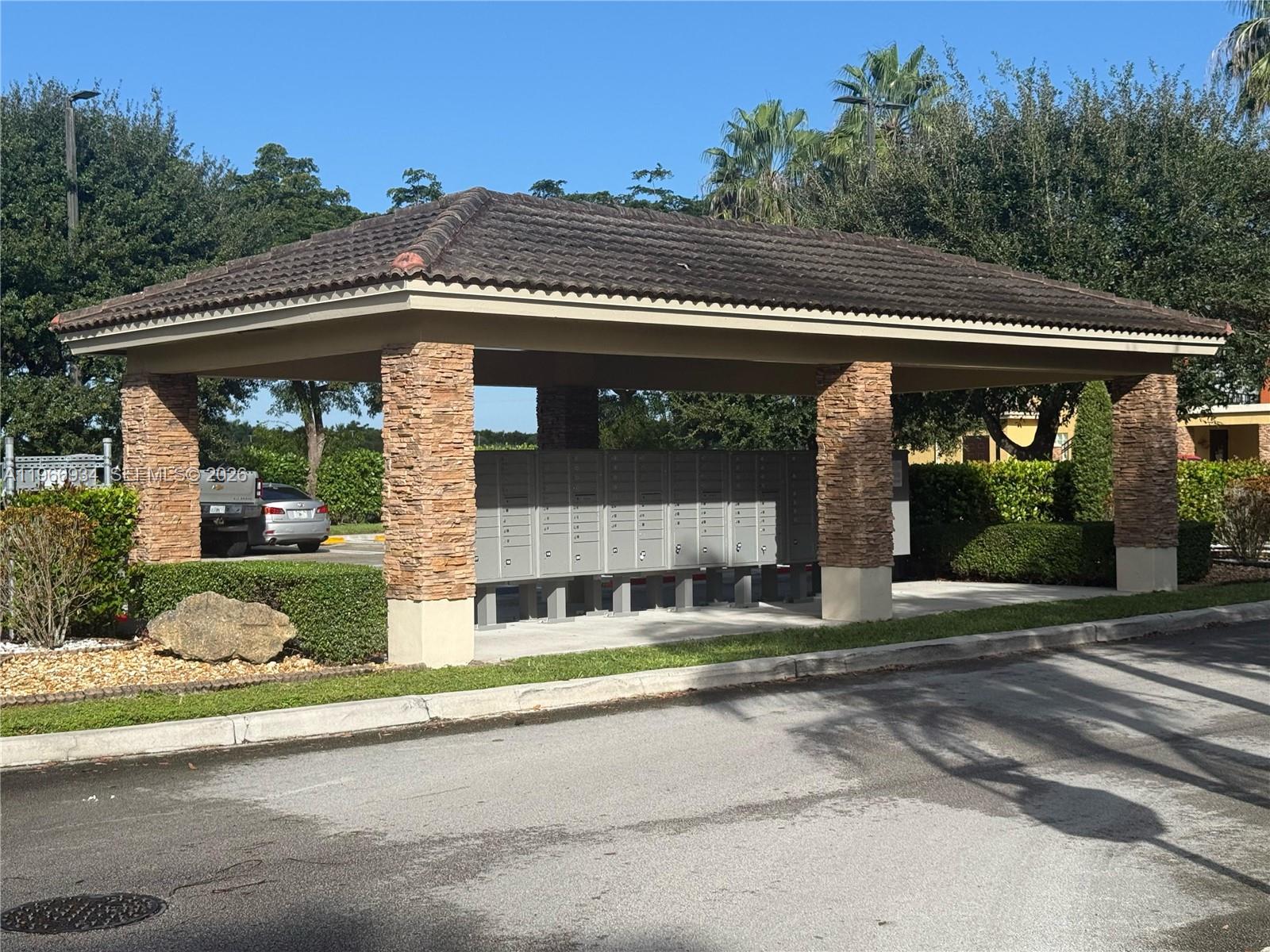 A covered outdoor structure with stone pillars houses a large bank of metal mailboxes — 930 NE 34th Ave # 201, Homestead FL 33033, HOMESTEAD, FL