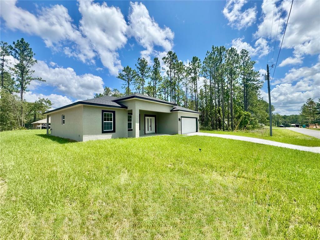 A modern single-story house with a light-colored stucco exterior and a two-car garage — 1905 W LINDEN DRIVE, CITRUS SPRINGS, FL