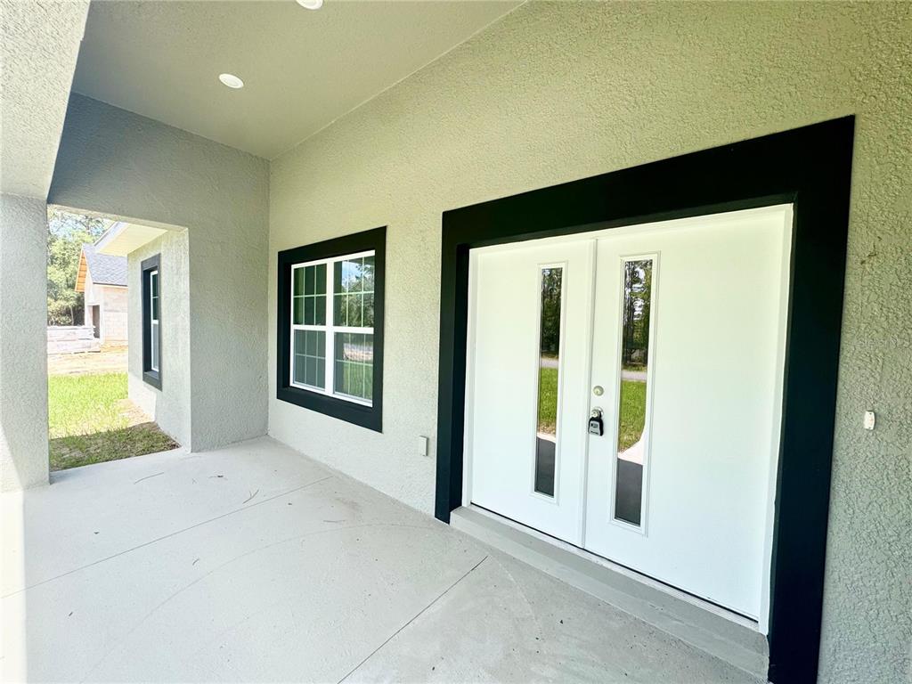 A covered entryway features a white double door with glass panels and a black frame — 1905 W LINDEN DRIVE, CITRUS SPRINGS, FL