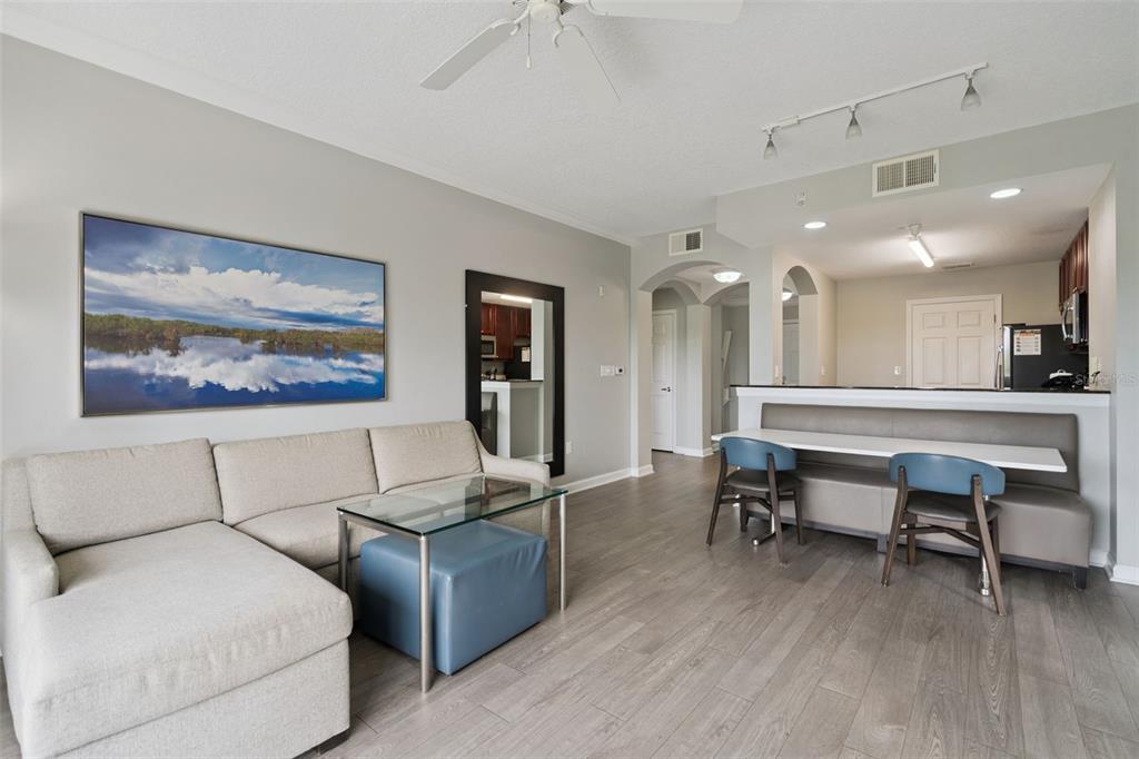 A living room and dining area with light wood floors, a sectional sofa, and seating — 14501 GROVE RESORT AVENUE UNIT 1726, WINTER GARDEN, FL