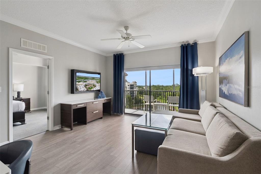 A living room with wood-look flooring, a sectional sofa, a television, and a balcony view — 14501 GROVE RESORT AVENUE UNIT 1726, WINTER GARDEN, FL