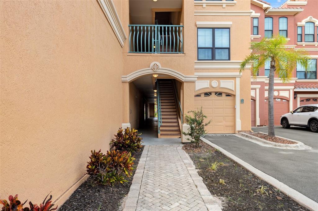 A paved walkway leads to an arched entryway with stairs and a garage door — 2738 VIA TIVOLI UNIT 234A, CLEARWATER, FL