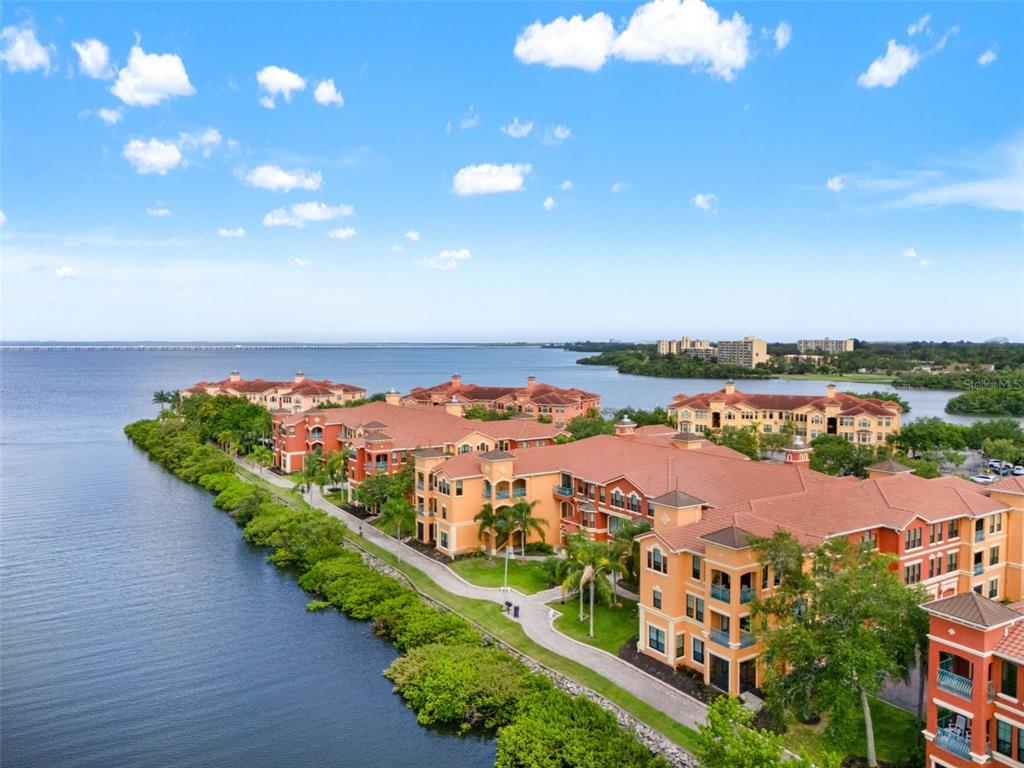 An aerial view of orange apartment buildings along a waterfront with a paved walking path — 2738 VIA TIVOLI UNIT 234A, CLEARWATER, FL