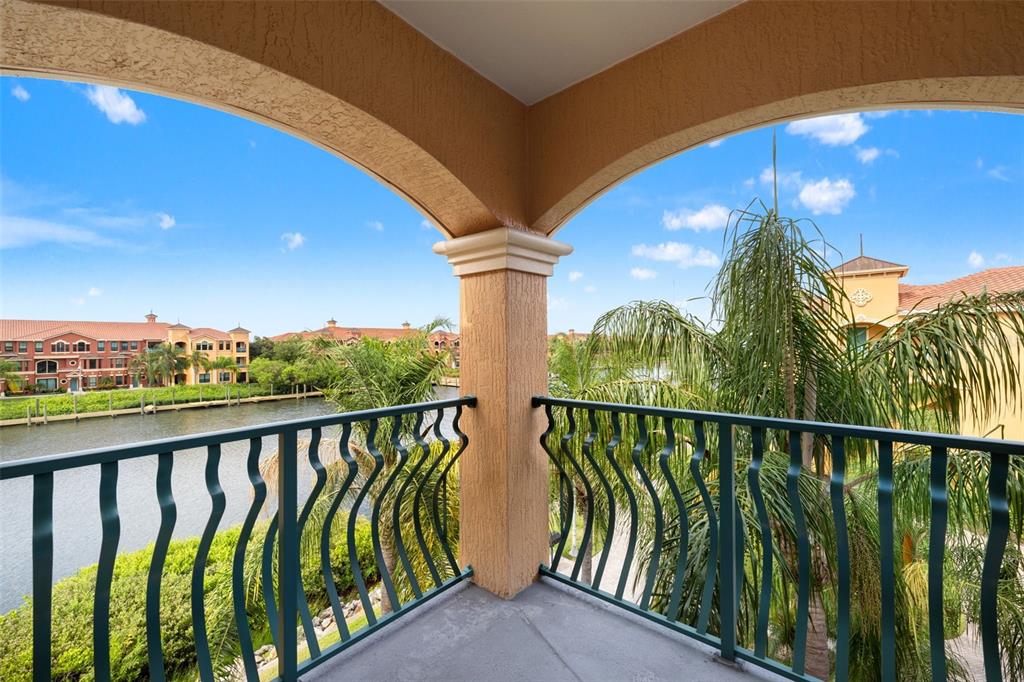 A covered balcony with a metal railing overlooks a canal and nearby apartment buildings — 2738 VIA TIVOLI UNIT 234A, CLEARWATER, FL
