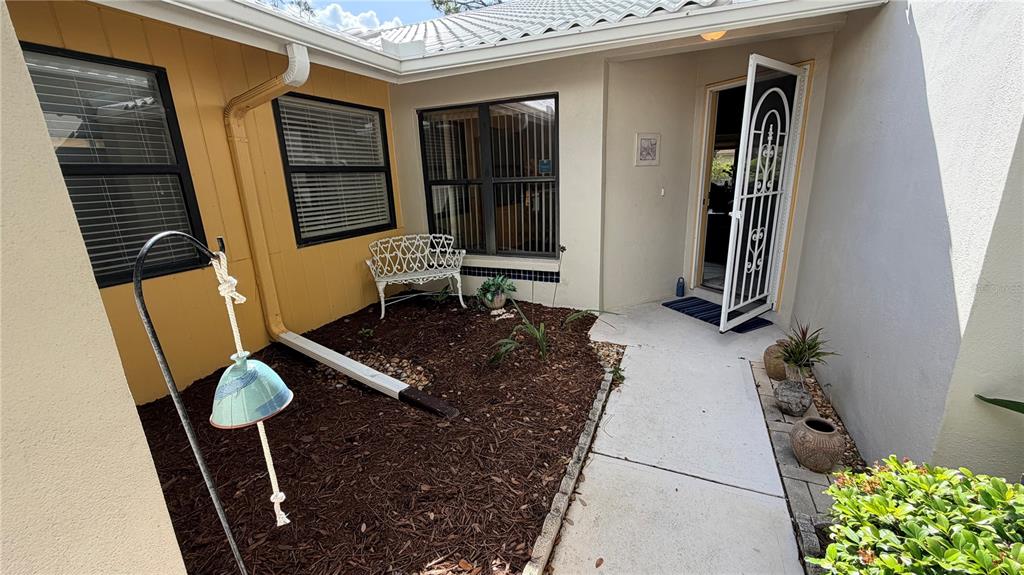 A small courtyard features a white metal bench, mulch landscaping, and a front entryway — 227 SOUTHAMPTON DRIVE UNIT 289, VENICE, FL