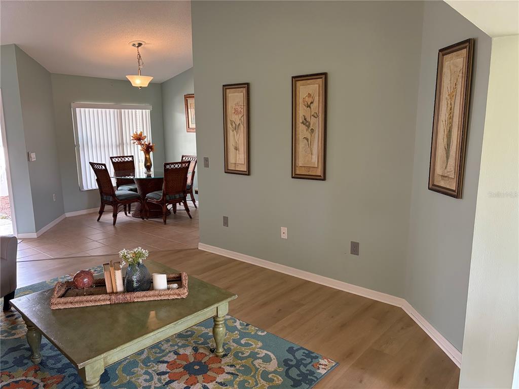 A living area with light wood floors leads to a dining room with tile flooring — 227 SOUTHAMPTON DRIVE UNIT 289, VENICE, FL