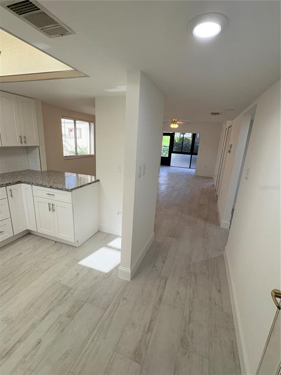 A kitchen with white cabinets and granite countertops opens into a light-floored living area — 16340 DUBLIN CIRCLE UNIT 101, FORT MYERS, FL
