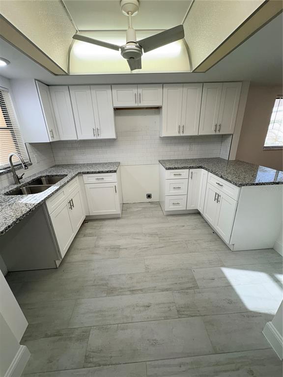 A kitchen with white cabinets, granite countertops, subway tile backsplash, and light wood-look tile flooring — 16340 DUBLIN CIRCLE UNIT 101, FORT MYERS, FL