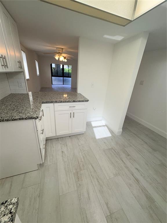 A kitchen with white cabinets, granite countertops, and light wood-look tile flooring — 16340 DUBLIN CIRCLE UNIT 101, FORT MYERS, FL