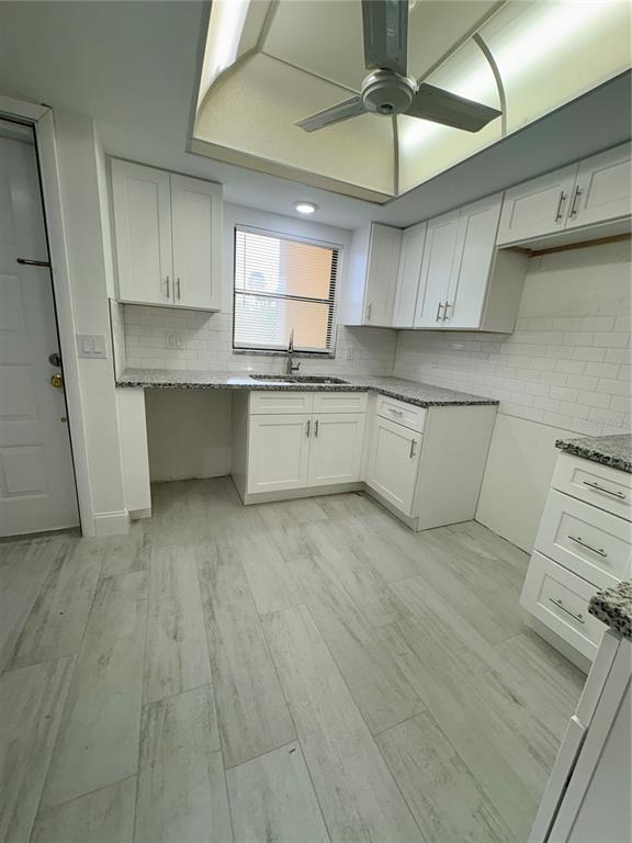 A kitchen features white cabinets, granite countertops, subway tile backsplash, and light wood-look flooring — 16340 DUBLIN CIRCLE UNIT 101, FORT MYERS, FL