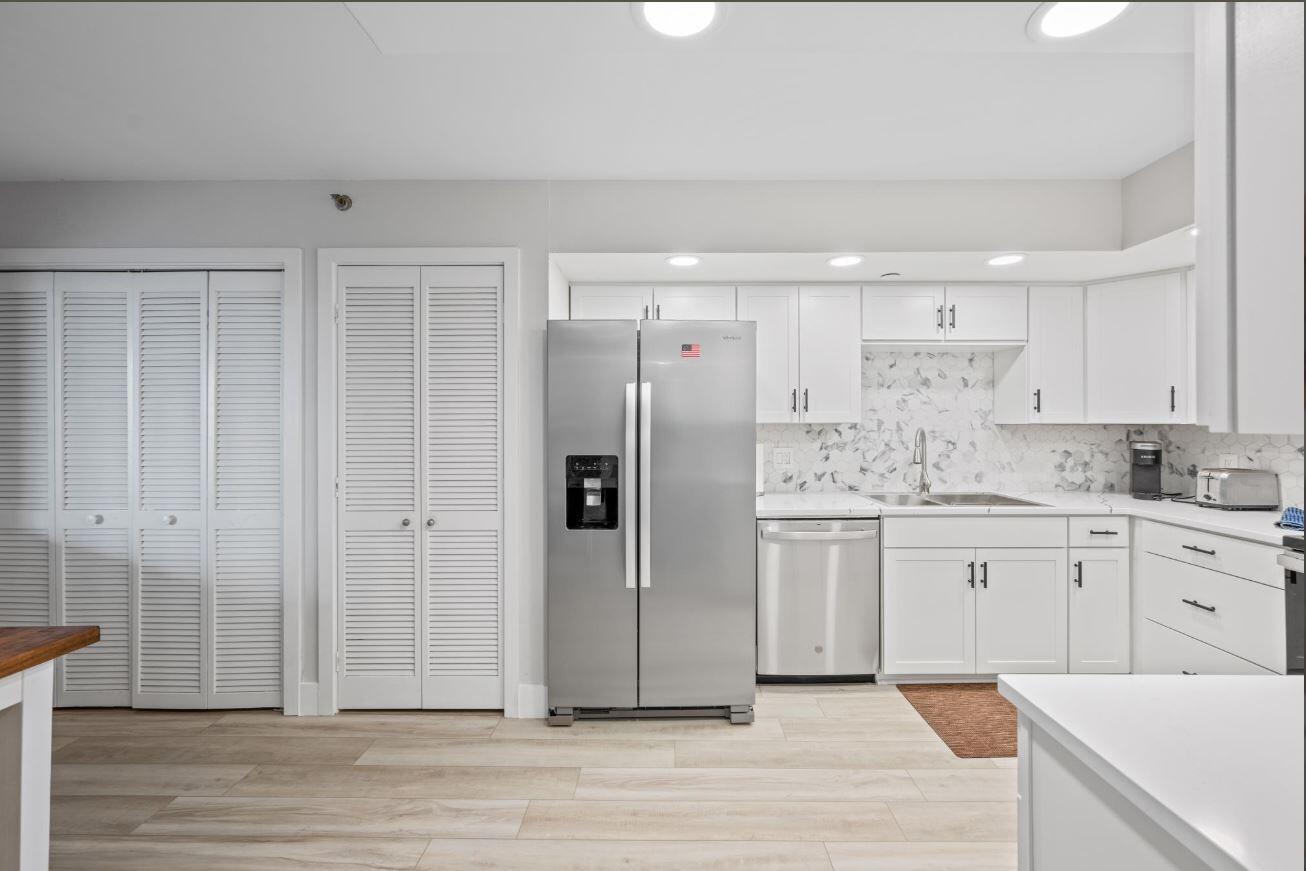 A kitchen with white cabinets, stainless steel appliances, and light wood-look flooring — 500 Ocean Trail Way # 506, Jupiter FL 33477, JUPITER, FL