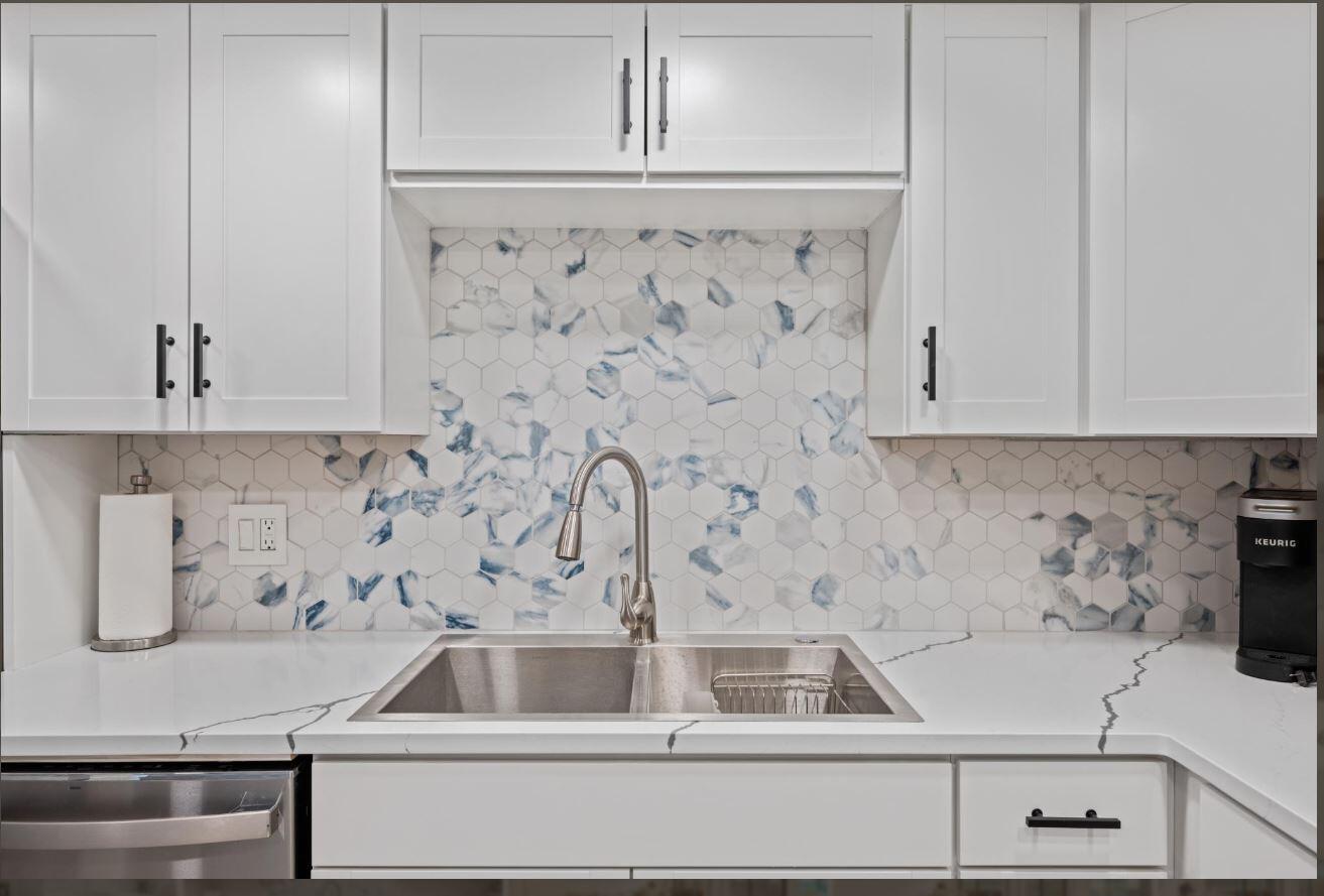 A kitchen sink area features white cabinets, a marble-veined countertop, and a blue-patterned hexagonal backsplash — 500 Ocean Trail Way # 506, Jupiter FL 33477, JUPITER, FL