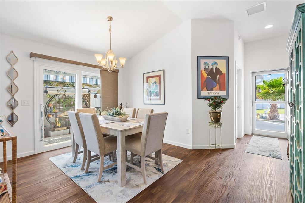 A dining room features a wooden table, upholstered chairs, a chandelier, and a glass door — 1773 BLACKWELL LANE, THE VILLAGES, FL