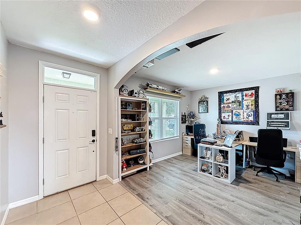 A home office with gray wood-look flooring, a white bookshelf, and Star Wars decor — 3689 MAIDENCAIN STREET, CLERMONT, FL