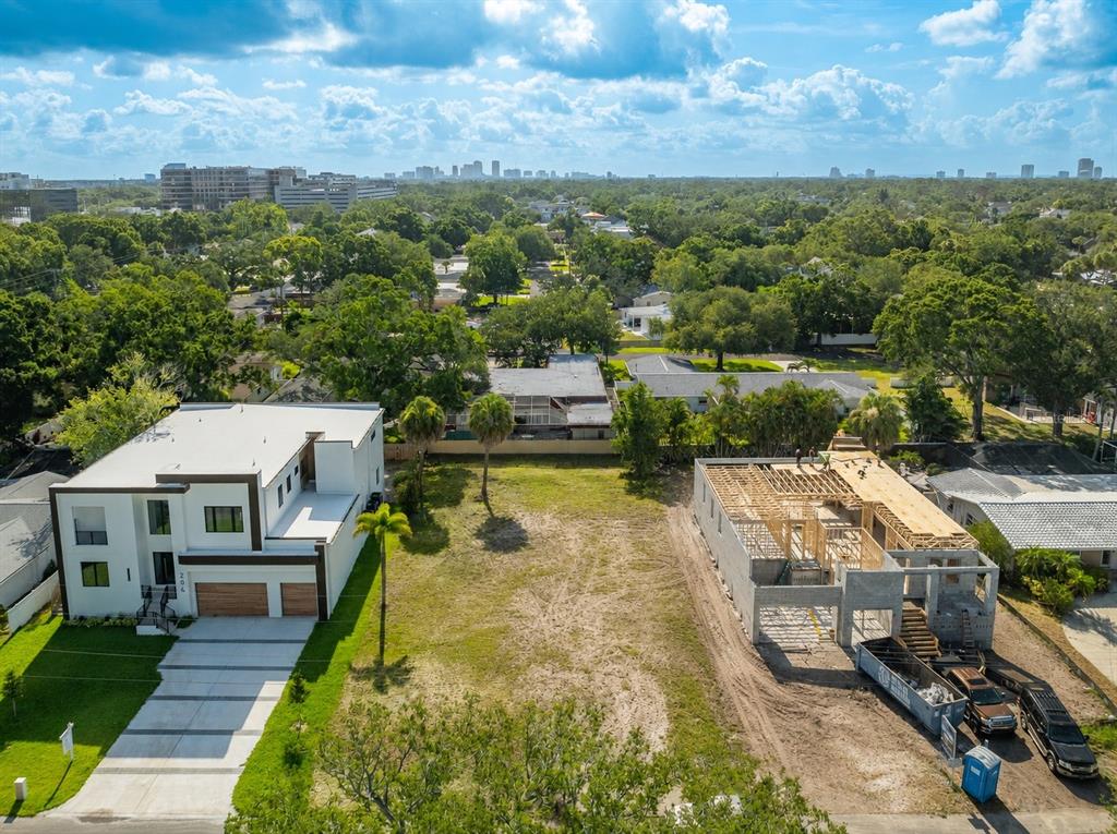 An aerial view shows a vacant lot situated between a completed modern house and construction — 208 S TREASURE DRIVE, TAMPA, FL
