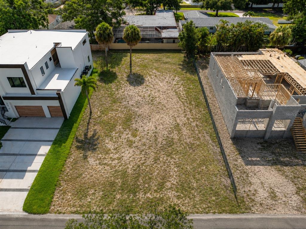 An aerial view shows a vacant residential lot situated between two modern houses under construction — 208 S TREASURE DRIVE, TAMPA, FL