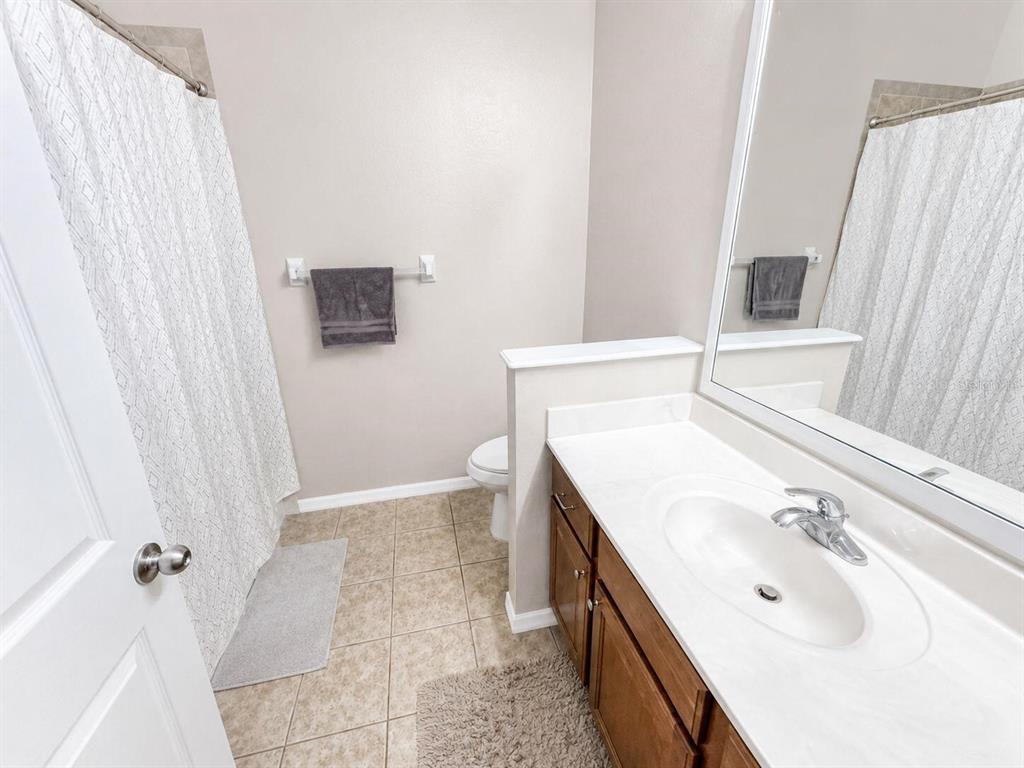 A bathroom features a vanity with a white countertop, a toilet, and a shower curtain — 9964 NW 22ND ROAD, GAINESVILLE, FL