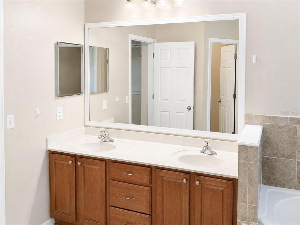 A bathroom features a double-sink vanity with wood cabinets, a white countertop, and a large mirror — 9964 NW 22ND ROAD, GAINESVILLE, FL