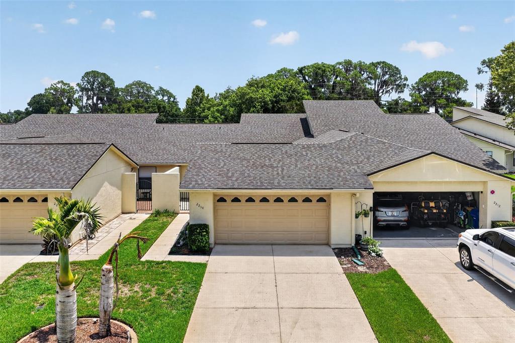 An exterior view of a single-story townhouse complex with a multi-car garage and driveway — 2214 CYPRESS COVE DRIVE UNIT 4, TAVARES, FL