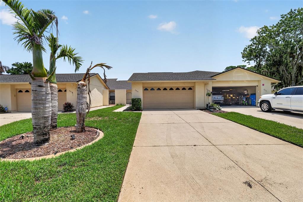 A single-story house with a beige exterior, a two-car garage, and a concrete driveway — 2214 CYPRESS COVE DRIVE UNIT 4, TAVARES, FL