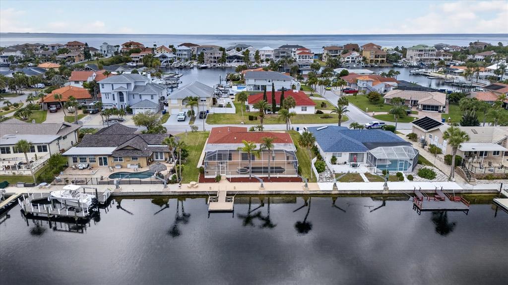 An aerial view shows waterfront houses with private docks and swimming pools along a canal — 5110 PORPOISE PLACE, NEW PORT RICHEY, FL