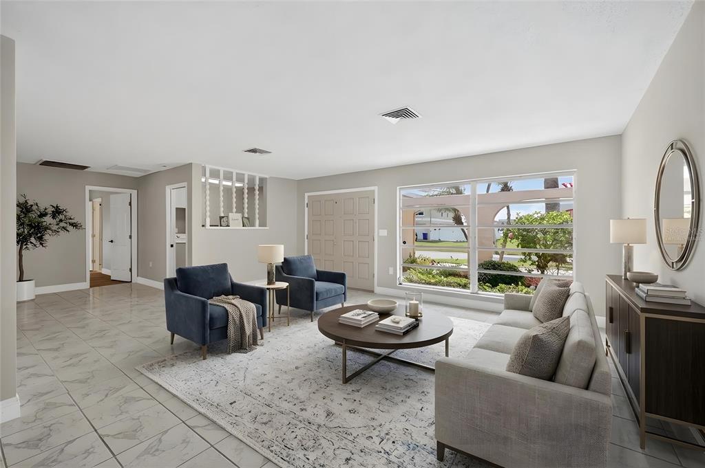 A living room features light tile floors, a large area rug, blue armchairs, and a sofa — 5110 PORPOISE PLACE, NEW PORT RICHEY, FL