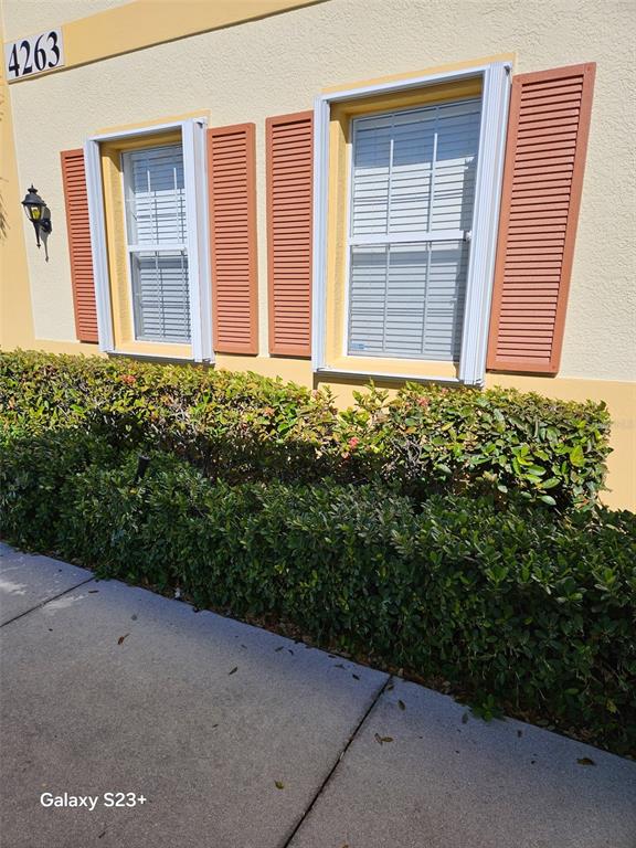 A beige building exterior features two windows with orange shutters and a green hedge — 4263 LIRON AVENUE UNIT 101, FORT MYERS, FL