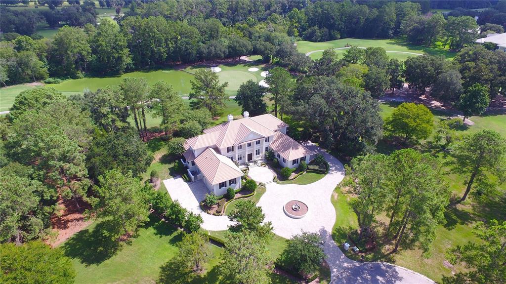 An aerial view of a large house with a tile roof, circular driveway, and fountain — 4026 NW 85TH TERRACE, OCALA, FL