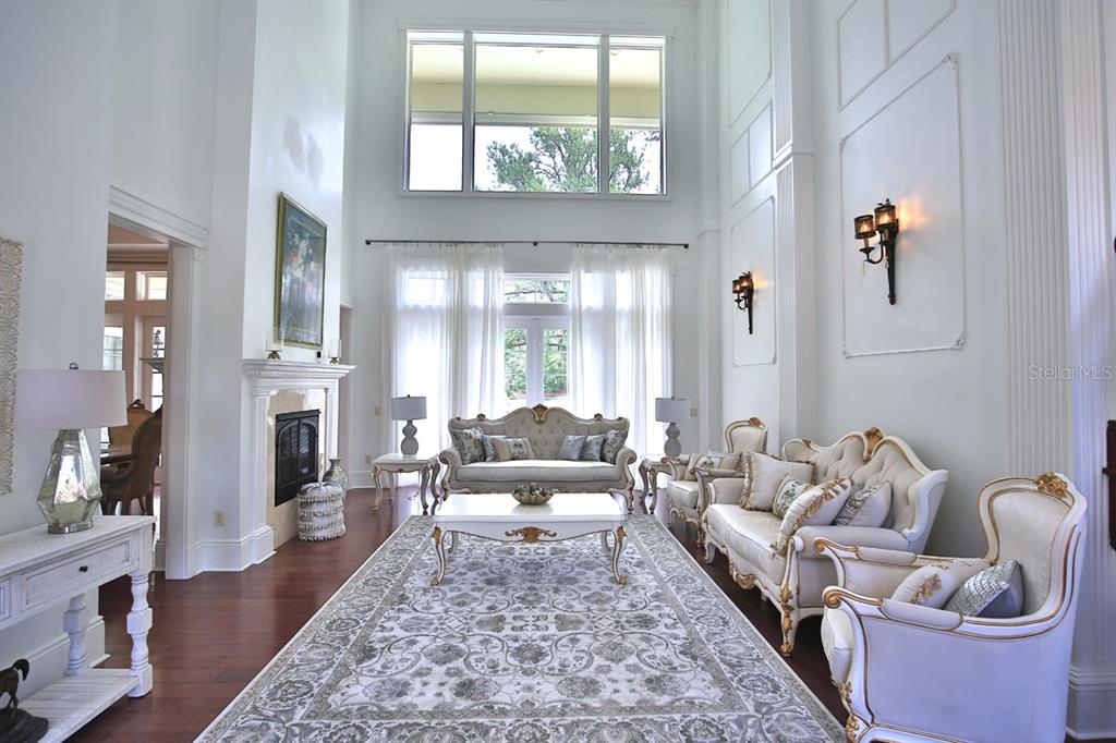 A formal living room features high ceilings, a fireplace, and elegant white furniture on hardwood — 4026 NW 85TH TERRACE, OCALA, FL