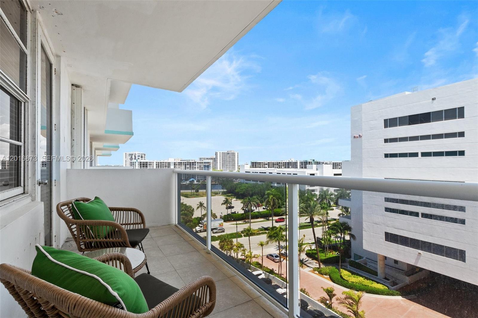 A balcony with two wicker chairs overlooks a parking lot and surrounding apartment buildings — 3725 S Ocean Dr # 921, Hollywood FL 33019, HOLLYWOOD, FL