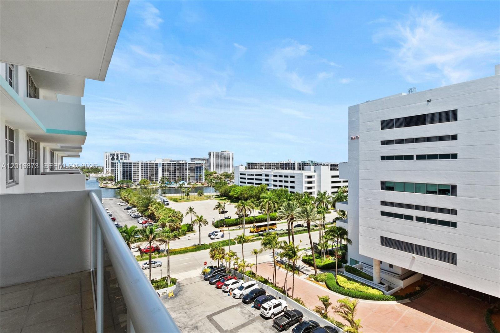 A high-angle view from a balcony overlooks a parking lot, palm trees, and nearby buildings — 3725 S Ocean Dr # 921, Hollywood FL 33019, HOLLYWOOD, FL